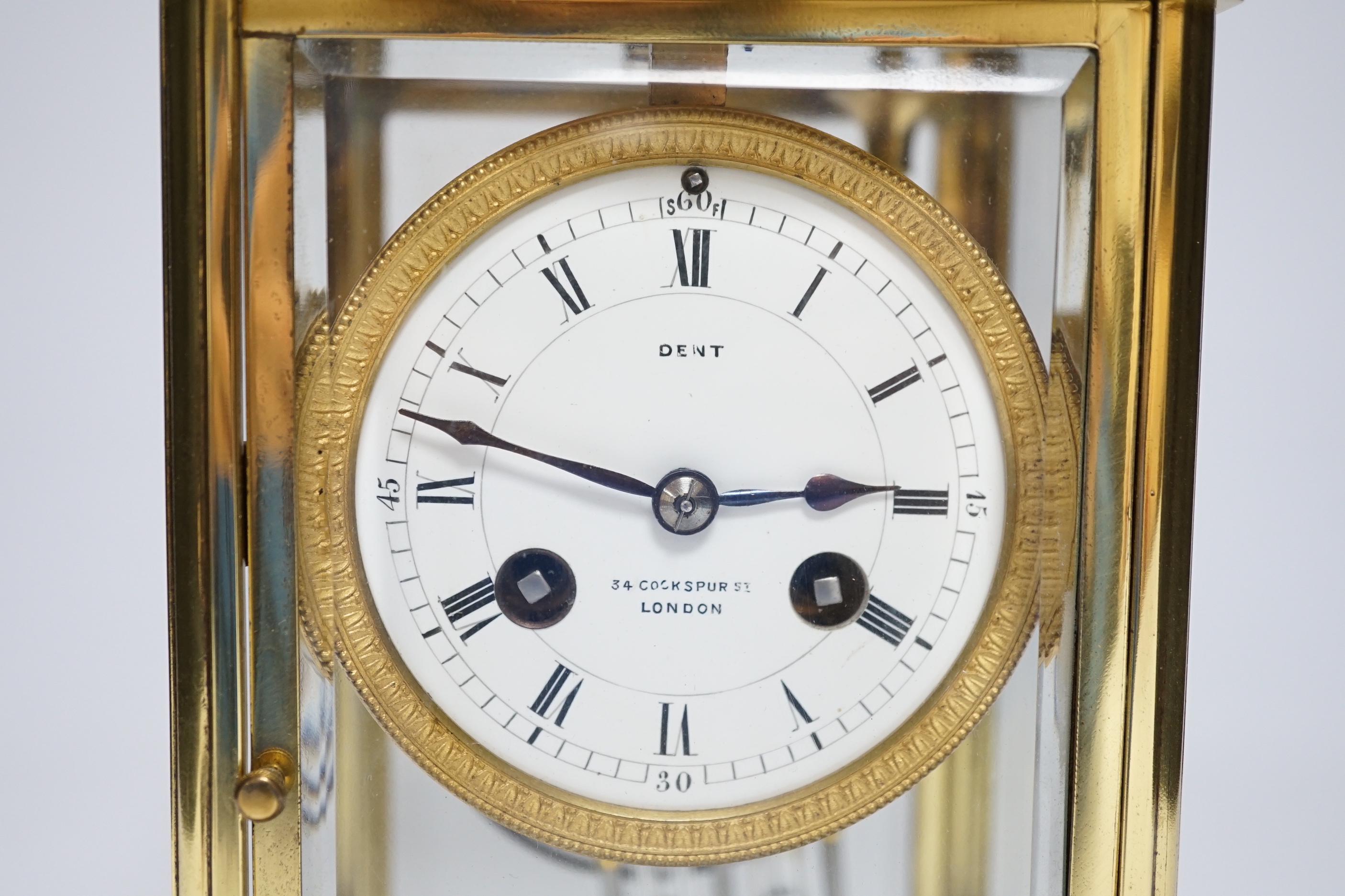 An early 20th century brass four glass clock retailed by Dent, 22cm
